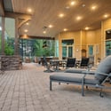 Huge covered patio designed for outdoor dining and entertaining, complete with custom pavers, forest views, and spacious seating throughout.