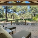 Expansive covered patio overlooking scenic golf course greens and pine trees, offering incredible outdoor relaxation and entertaining opportunities.