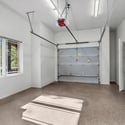 Large garage with epoxy flooring, bright lighting, and high ceilings offering excellent storage and parking flexibility for multiple vehicles.