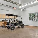 Well-appointed garage featuring built-in storage cabinets, epoxy-coated flooring, heating system, and dedicated golf cart parking space.
