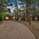 Gorgeous custom home surrounded by mature pine trees featuring a grand driveway, elegant architecture, and impressive outdoor presence in Flagstaff.