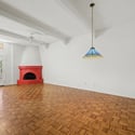 Large great room featuring soaring ceilings, exposed beams, parquet flooring, and a dramatic fireplace. The open floor plan creates an ideal gathering space for family and guests.