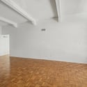 Open-concept living room showcasing soaring ceilings, exposed beams, and attractive parquet flooring. The spacious layout provides a welcoming environment for everyday living and entertaining.