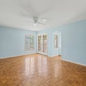Bright primary bedroom with ample floor space, elegant French doors, and natural light. The room's flexible layout easily accommodates a variety of bedroom furniture arrangements.