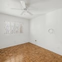 Bright guest bedroom showcasing plantation shutters, warm parquet flooring, and a neutral palette. A comfortable space ready to serve as a bedroom, office, or creative workspace.