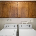 Well-equipped laundry area with overhead storage cabinets, washer and dryer setup, and practical organization space. Designed to support convenient household routines.