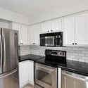Contemporary kitchen showcasing stainless steel appliances, white cabinetry, subway tile accents, and updated finishes. Designed for both efficiency and style, this kitchen is ready for everyday living.