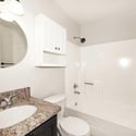 Well-maintained guest bathroom featuring a spacious vanity, updated lighting, convenient storage, and a tub-shower combination. Neutral finishes create a clean and inviting space.