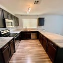 Stylish kitchen with granite countertops, stainless steel appliances, dark cabinets, and generous workspace. An ideal setup for cooking, hosting, and family gatherings.