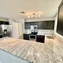 Well-appointed kitchen featuring extensive granite surfaces, stainless steel appliances, abundant storage, and a practical layout designed for modern living.