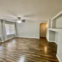 Expansive great room featuring durable wood-look flooring, large windows, and decorative built-in niches. The open layout creates a welcoming environment for relaxing and entertaining.