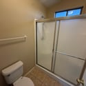 Well-maintained bathroom with a full-size shower, sliding glass enclosure, and tile flooring. Natural light enhances the space while neutral tones provide timeless appeal.