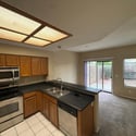 Bright kitchen featuring stainless steel appliances, extensive cabinet storage, and a breakfast bar that seamlessly connects to the living room. Backyard access enhances indoor-outdoor living opportunities.