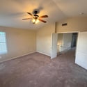 Spacious primary bedroom offering plush carpeting, ceiling fan, and abundant natural light. The generous layout provides flexibility for additional seating or workspace arrangements.