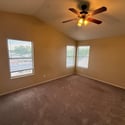 Light-filled bedroom featuring vaulted ceilings, multiple windows, and comfortable living space. A welcoming room with versatile use and attractive architectural character.