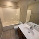 Full bathroom with combination tub and shower, large vanity mirror, tile flooring, and practical storage. Neutral finishes create a timeless and move-in-ready appearance.