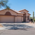 Welcoming front fa ade featuring an arched entry, mature landscaping, and an oversized driveway leading to a three-car garage. A beautiful introduction to this spacious Terracina home.