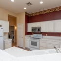 Open kitchen showcasing extensive tile counters, breakfast bar seating, abundant cabinetry, and recessed lighting. Designed to keep the chef connected to family and guests throughout the home.