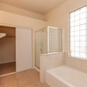 Primary bath featuring a relaxing soaking tub, separate glass-enclosed shower, and natural light from a glass block window. A comfortable space for unwinding after a long day.