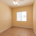 Secondary bedroom with tile flooring, ceiling fan, and natural light. This adaptable room can easily serve as a guest suite, home office, study area, or personal retreat.