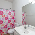 Bright hall bathroom featuring a spacious vanity, large mirror, and full tub-shower setup. A practical and comfortable space designed to accommodate guests and daily living needs.