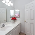 Well-appointed bathroom showcasing dual sinks, generous counter space, and updated lighting. The functional layout offers convenience for busy households and visiting guests.