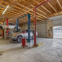 Expansive workshop interior featuring automotive lifts, multiple service bays, high ceilings, and abundant work space. Designed for serious vehicle enthusiasts, restoration projects, or commercial-style storage.