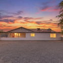 Beautiful front elevation showcasing the home's spacious lot, mature trees, and expansive grounds. Enjoy exceptional privacy and flexibility with over two acres of usable land in Goodyear.