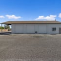 Detached multi-bay workshop with oversized garage doors, covered exterior parking, and expansive work areas designed for vehicle storage, restoration projects, equipment, or business use.