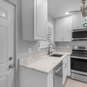 Updated kitchenette features sleek white cabinetry, stainless steel appliances, modern countertops, and efficient storage, creating a stylish and functional living environment.