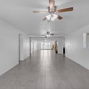 Large open-concept living area provides endless furniture arrangement possibilities with updated flooring, multiple ceiling fans, and generous natural light throughout the home.