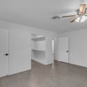 Comfortable primary suite offers updated flooring, ceiling fan, neutral finishes, and convenient access to the walk-in closet and remodeled ensuite bathroom for everyday comfort.