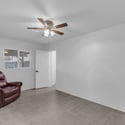 Spacious secondary bedroom offers updated tile flooring, ceiling fan, abundant natural light, and convenient access to the adjoining bathroom, making it ideal for guests or a home office.