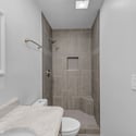 Stylish walk-in shower showcases floor-to-ceiling tile, built-in storage niche, and modern finishes, creating a comfortable and elegant bathroom designed for everyday living.