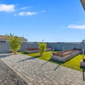 Backyard highlights raised planter boxes, paver walkways, artificial turf, and low-maintenance landscaping, creating an inviting outdoor space for gardening and entertaining.