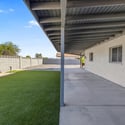 Expansive covered patio complements the spacious backyard with artificial turf and easy-care landscaping, providing a comfortable extension of the home's living space.