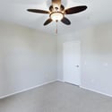 The generous owner's suite features plush carpeting, ceiling fan, neutral finishes, and convenient access to the adjoining bathroom, creating a peaceful and functional living space.