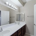The bathroom showcases a dual-sink vanity with expansive countertop space, large mirror, and abundant cabinet storage, providing both convenience and functionality for everyday living.