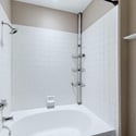 The bathroom features a full tub and shower combination with clean tile surrounds, convenient shelving, and neutral finishes that create a bright, functional space for everyday comfort.
