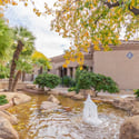 This beautifully landscaped courtyard features a decorative fountain, mature trees, natural stone accents, and lush greenery, creating a peaceful outdoor retreat within this highly desirable Scottsdale condominium community.