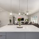 Overlooking the open living area, the expansive kitchen island creates a seamless space for entertaining and everyday living. Large windows bring in abundant natural light throughout the home.