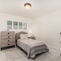 Bright secondary bedroom featuring plantation shutters, updated tile flooring, and versatile space ideal for guests, children, or a dedicated home office.