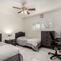 Spacious guest bedroom with dual sleeping areas, plantation shutters, tile flooring, and room for work or study. A practical layout suited for growing households.