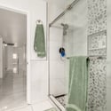 Designer walk-in shower with frameless glass enclosure, decorative pebble tile accents, built-in storage niche, and modern fixtures that enhance this updated Scottsdale home.