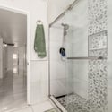 Alternate angle highlighting the spacious frameless shower, upgraded tile work, recessed shelving, and sleek finishes that complete this beautifully remodeled bathroom.