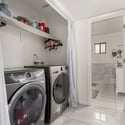 Dedicated laundry space with front-load appliances, utility sink, open shelving, and convenient storage designed to simplify daily household tasks.