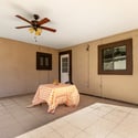Covered patio with ceiling fan, durable tile flooring, and space for outdoor seating creates a comfortable extension of the home's living area. Ideal for entertaining or relaxing year-round in Scottsdale.