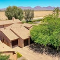 A stunning aerial view captures the home's elegant exterior, oversized paver driveway, mature landscaping, and scenic mountain backdrop. This Scottsdale property offers beautiful curb appeal and an exceptional residential setting.