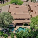 Enjoy a bird's-eye view of the beautifully landscaped backyard featuring a sparkling pool, spa, covered patio, and mature trees. This aerial image highlights the exceptional outdoor living offered by this Scottsdale property.