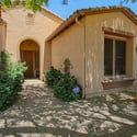 Mature desert landscaping, shaded walkways, and a covered front entrance create a welcoming approach to this beautifully maintained Scottsdale residence within a gated neighborhood.